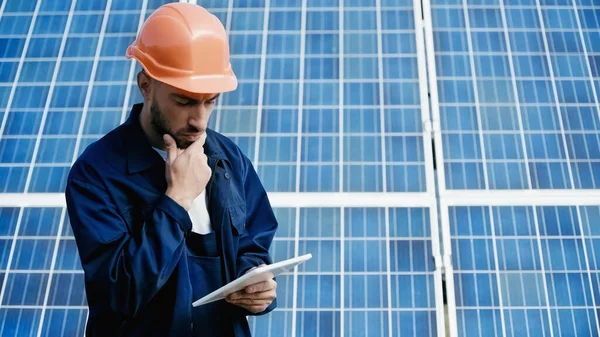 Pensive engineer using digital tablet near solar panel — Stock Photo