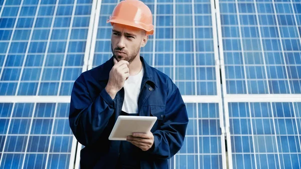 Thoughtful engineer using digital tablet near solar panel — Fotografia de Stock