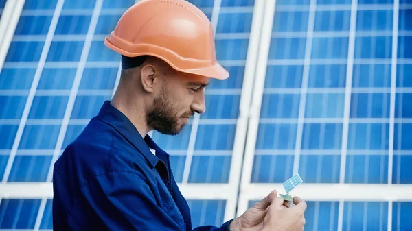 Smiling engineer looking at small model of solar panel — Stock Photo