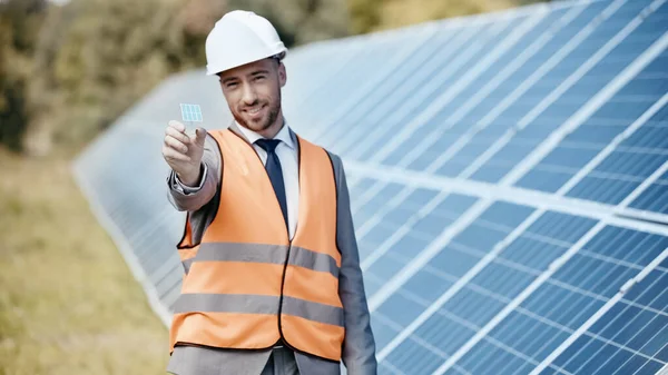 Homme d'affaires joyeux montrant petit modèle de batterie solaire — Photo de stock