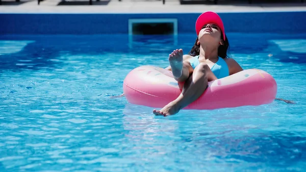 Giovane donna sul nuoto anello in piscina con acqua blu — Foto stock