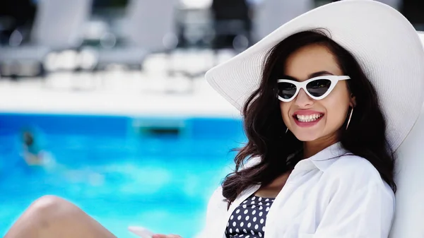 Fröhliche junge Frau mit Strohhut und stylischer Sonnenbrille — Stockfoto