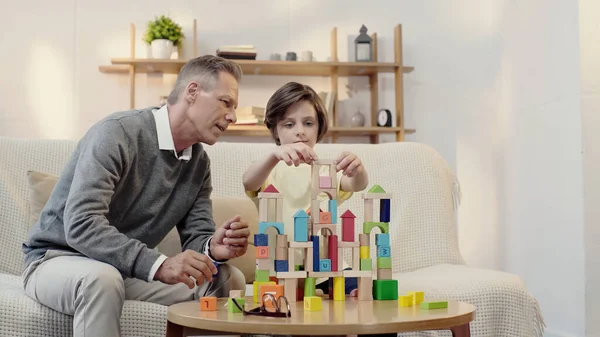 Middle aged grandfather playing building blocks with preteen boy — Stock Photo