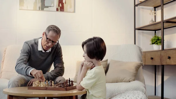 Avô e neto jogando xadrez na sala de estar — Fotografia de Stock