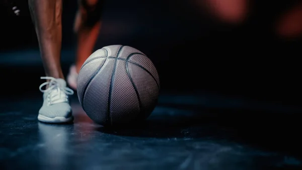 Cropped view of sportsman standing near basketball on dark background — Stock Photo
