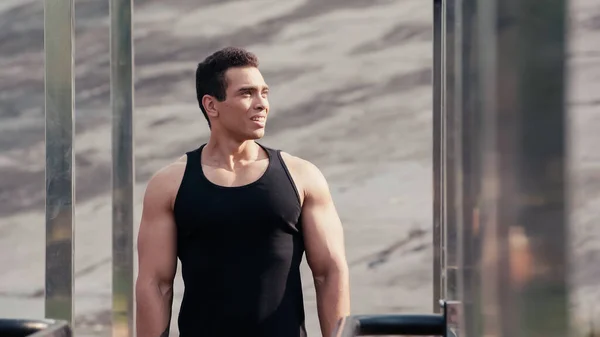 Athletic mixed race man looking away at outdoor gym on blurred foreground — Stock Photo
