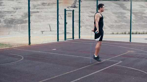 Vista a tutta lunghezza dell'uomo di razza mista che salta con corda da salto in palestra all'aperto — Foto stock