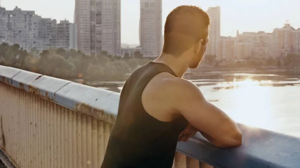 Bi-racial sportive man standing on bridge over river at dawn — Stock Photo