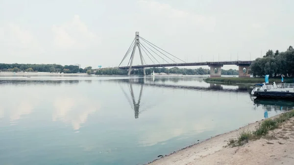 Bridge over wide river under cloudy sky — Stock Photo