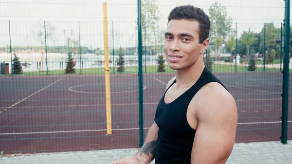 Спортивний бі-расовий чоловік з татуюванням дивиться на камеру в спортзалі на відкритому повітрі — стокове фото