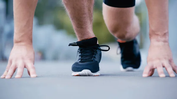 Cropped view of sportsman standing from start position outdoors — Stock Photo