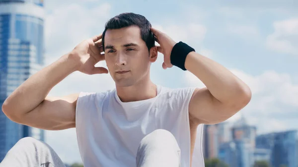 Young sportsman doing abs outdoors against blue sky — Stock Photo