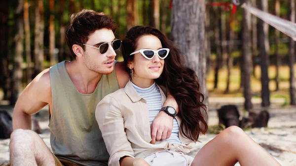 Man hugging smiling woman in sunglasses on beach — Stock Photo