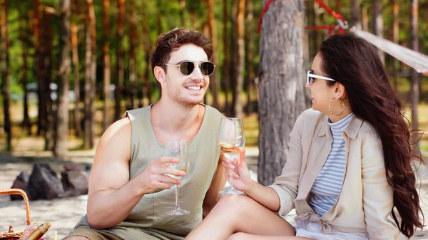 Позитивная пара, держащая вино во время пикника на пляже — стоковое фото