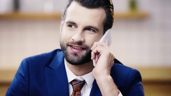 Cheerful businessman in suit talking on mobile phone in cafe — Stock Photo