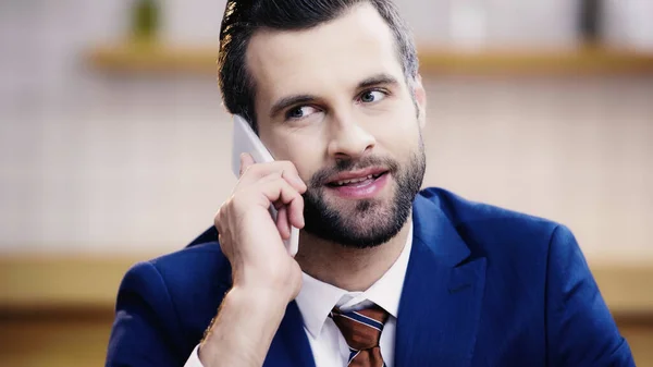 Bearded businessman in suit talking on mobile phone in cafe — Stock Photo