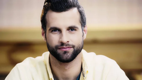 Bearded man in yellow shirt looking at camera — Stock Photo