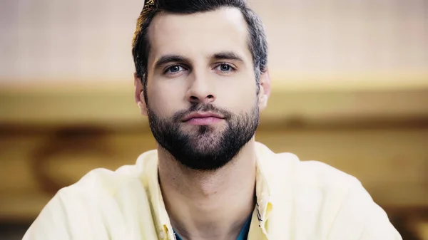 Confident man in yellow shirt looking at camera — Stock Photo