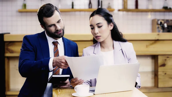 Bearded businessman and asian businesswoman working remotely in cafe — Stock Photo