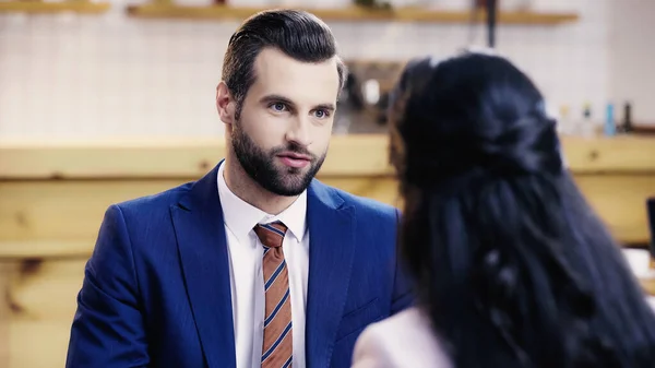 Businessman talking to blurred businesswoman in cafe — Stock Photo