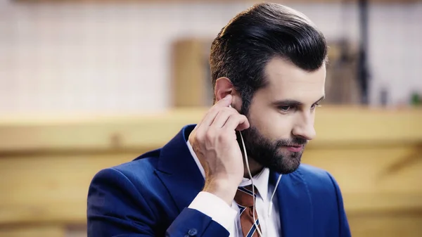 Homem de negócios barbudo em desgaste formal ajustando fone de ouvido — Fotografia de Stock