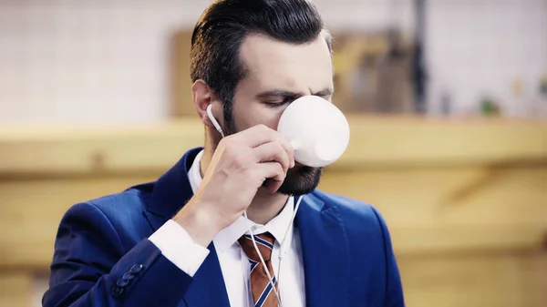 Hombre de negocios barbudo con auricular bebiendo café - foto de stock