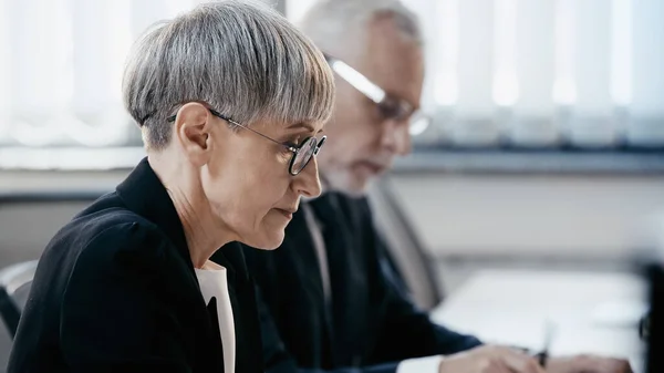 Вид збоку зрілої бізнес-леді в окулярах, що працюють в офісі — стокове фото
