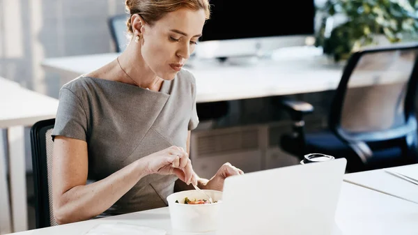 Бізнес-леді, що сидить біля салату, ноутбука та кави, щоб піти в офіс — стокове фото