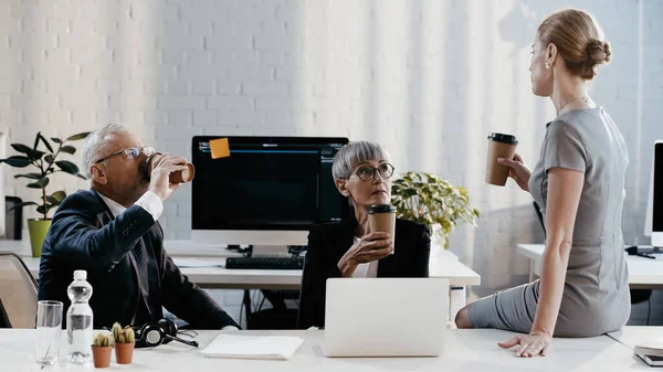 Business people holding coffee to go near devices and headset in office — Stock Photo