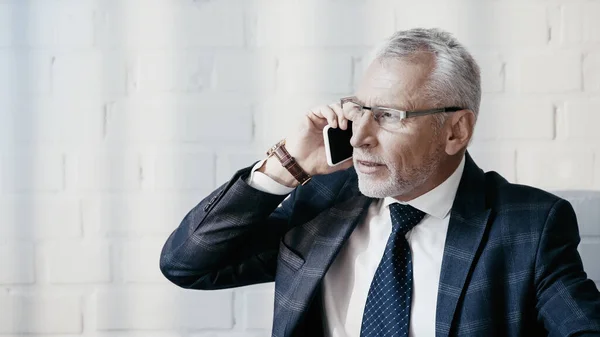 Empresario en ropa formal hablando por celular en la oficina - foto de stock