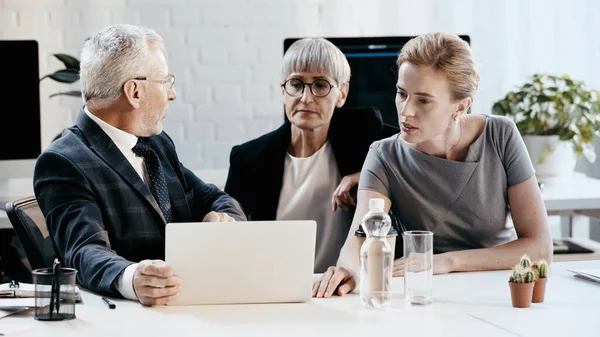 Geschäftsleute betrachten Laptop in der Nähe von Dokumenten im Büro — Stockfoto