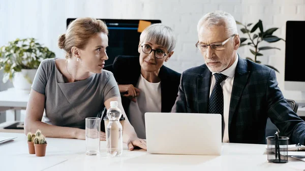 Geschäftsleute nutzen Laptop in der Nähe von Coffee to go und Wasser im Büro — Stockfoto