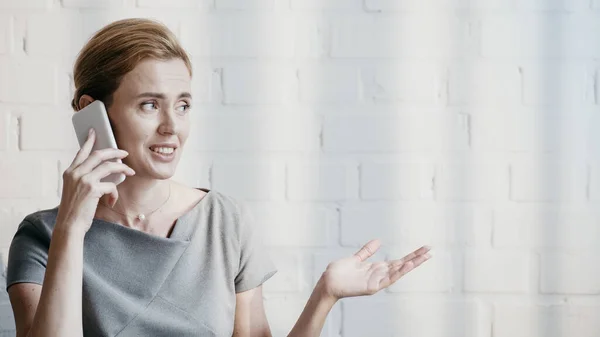 Smiling businesswoman talking on smartphone in office — Stock Photo