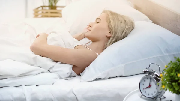 Jeune femme blonde avec les yeux fermés couché dans le lit — Photo de stock