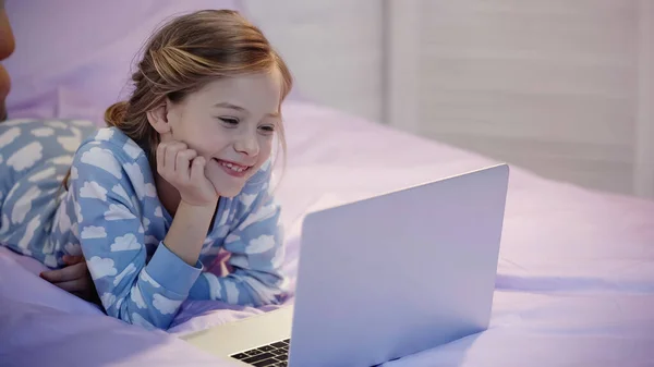 Happy preteen girl watching cartoons on laptop in bedroom — Stock Photo
