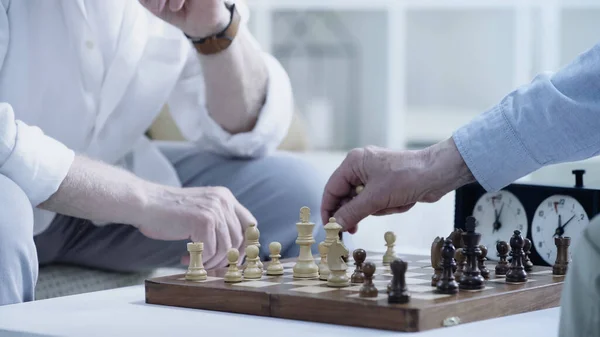 Cropped view of senior friends playing chess at home — Stockfoto