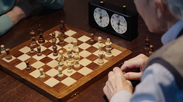 Обрізаний вид на старших чоловіків, які грають в шахи біля розмитого таймера — стокове фото