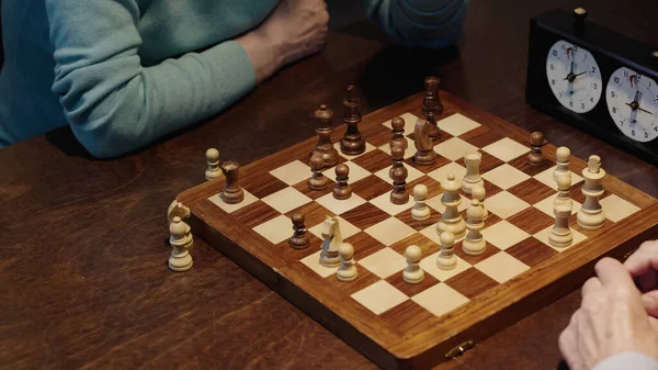 High angle view of chessboard near cropped senior men - foto de stock