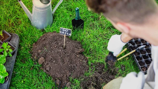 Blurred gardener holding shovel near soil and board with go green lettering in garden — Foto stock