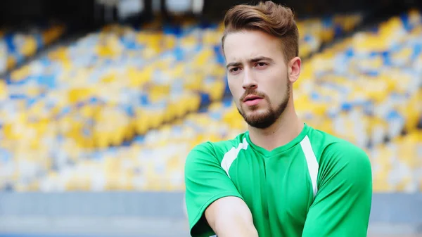 Bearded football player in green t-shirt warming up on stadium — Stock Photo