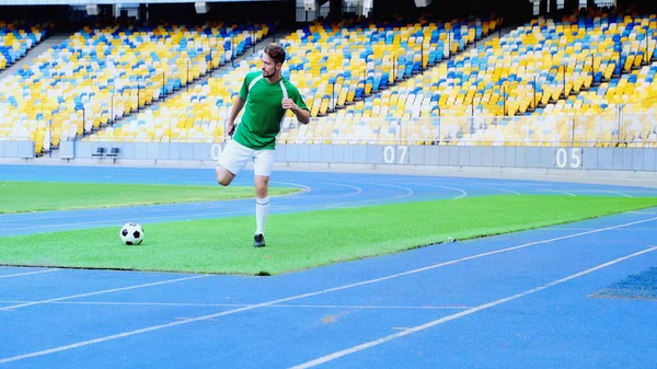 Full length of young and bearded football player in uniform warming up at stadium — Stockfoto