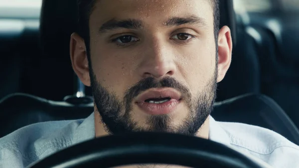 Young bearded man with sweaty forehead driving car in hot weather — Stock Photo