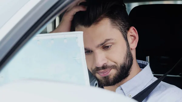 Discouraged man sitting in auto and looking at map — Photo de stock