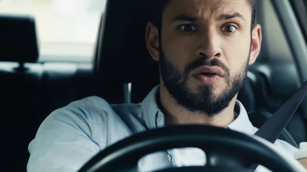 Наляканий і стурбований чоловік дивиться вперед під час водіння автомобіля — стокове фото
