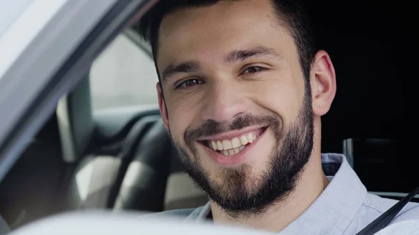 Portrait of cheerful man driving auto and looking at camera — Stockfoto