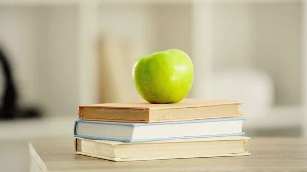 Green and fresh apple on stack of books on wooden desk — Fotografia de Stock