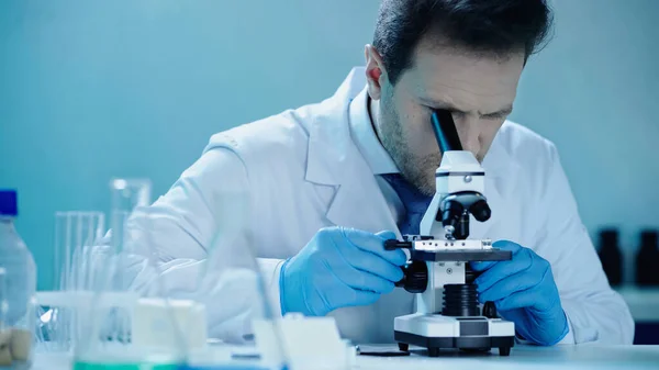 Науковець проводить дослідження під час перегляду мікроскопа в медичній лабораторії — стокове фото