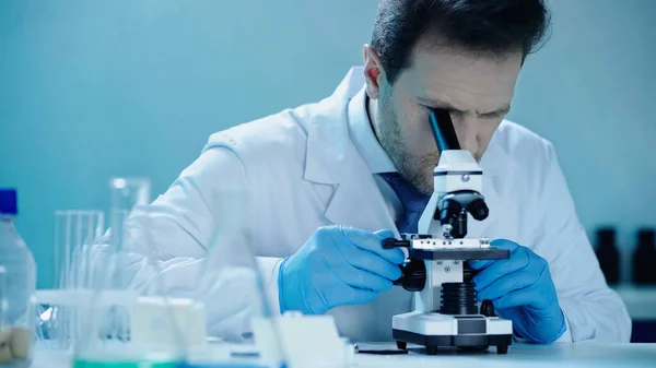 Scientist making research while looking through microscope in medical laboratory — Stock Photo