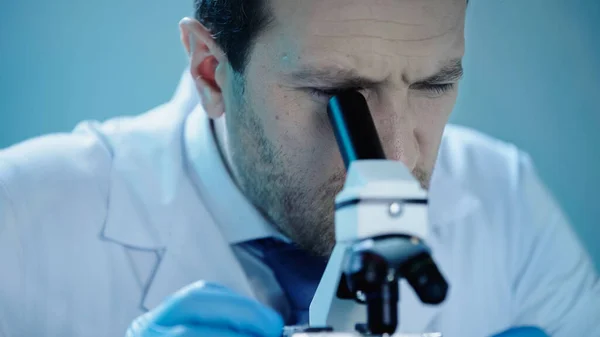 Scientist in white coat looking through microscope in laboratory — Stock Photo