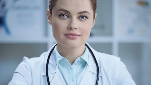 Cheerful doctor in white coat smiling and looking at camera — Stock Photo